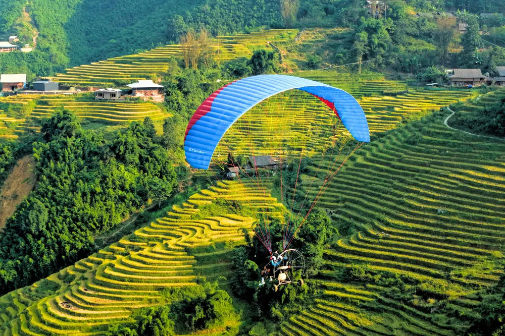 A paramotor gliding over a sun-drenched valley